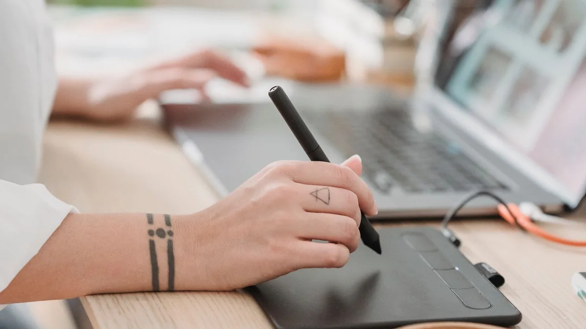 Designer working with a drawing tablet beside a laptop