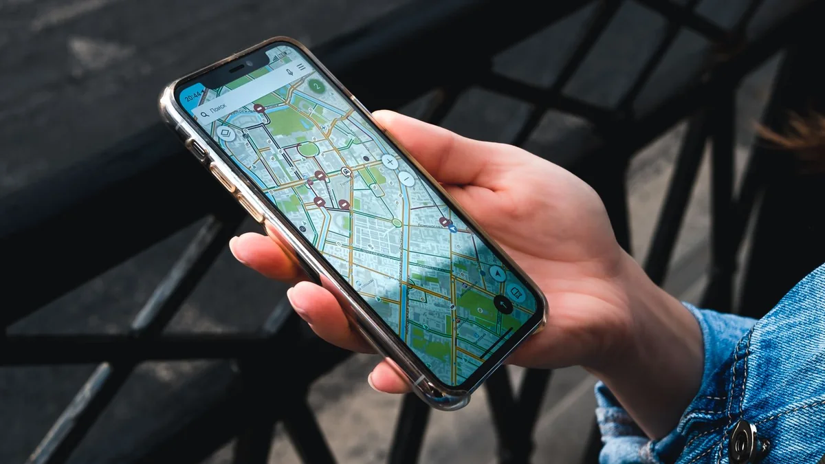 Person holding a smartphone displaying a map outdoors