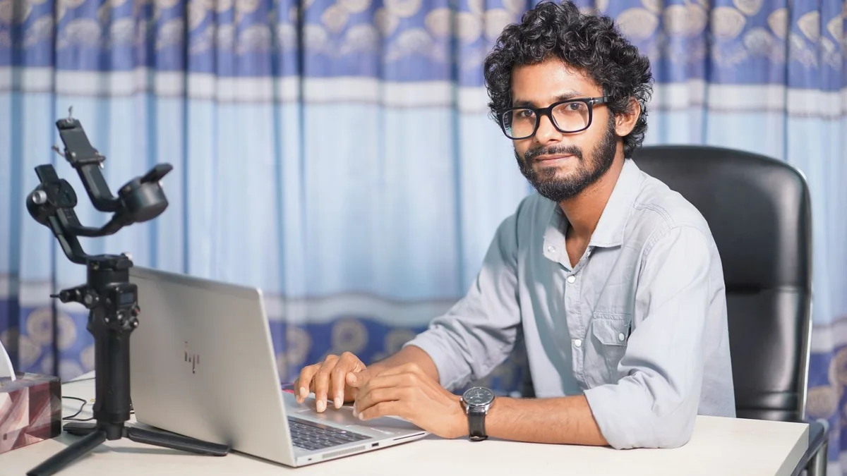 Web professional seated at a desk with a laptop and camera equipment
