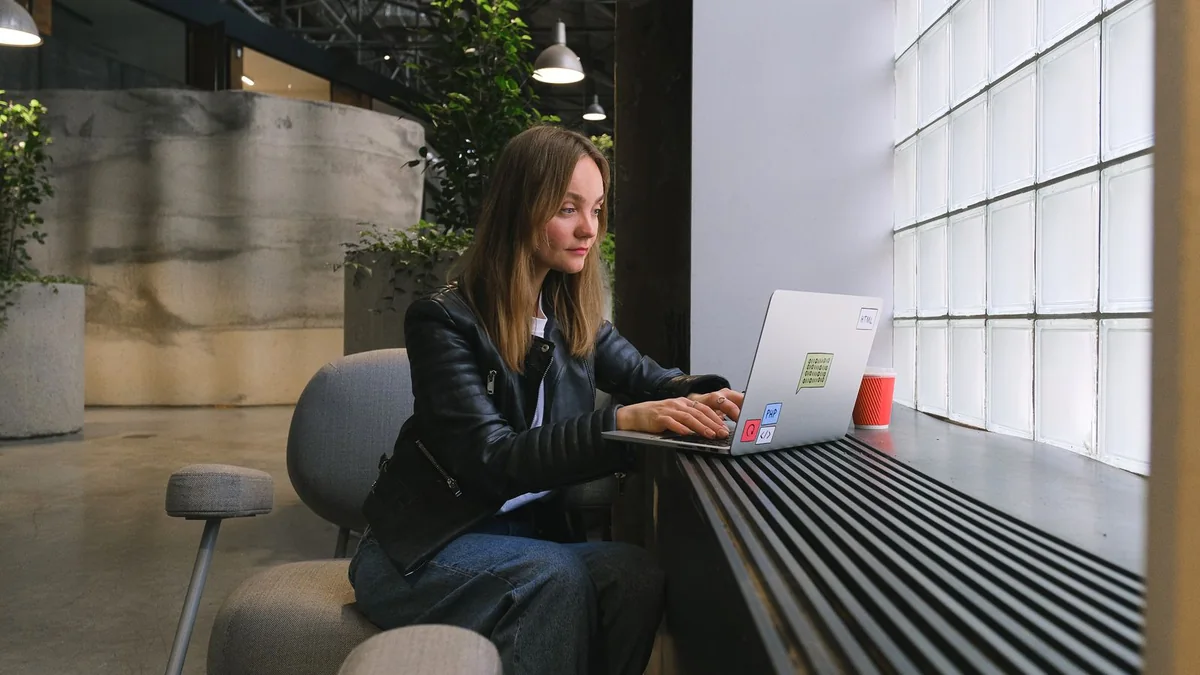 Professional working on a laptop beside a bright office window