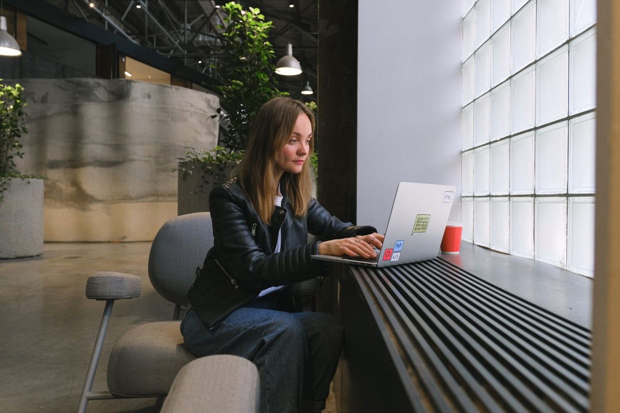 Professional working on a laptop beside a bright office window
