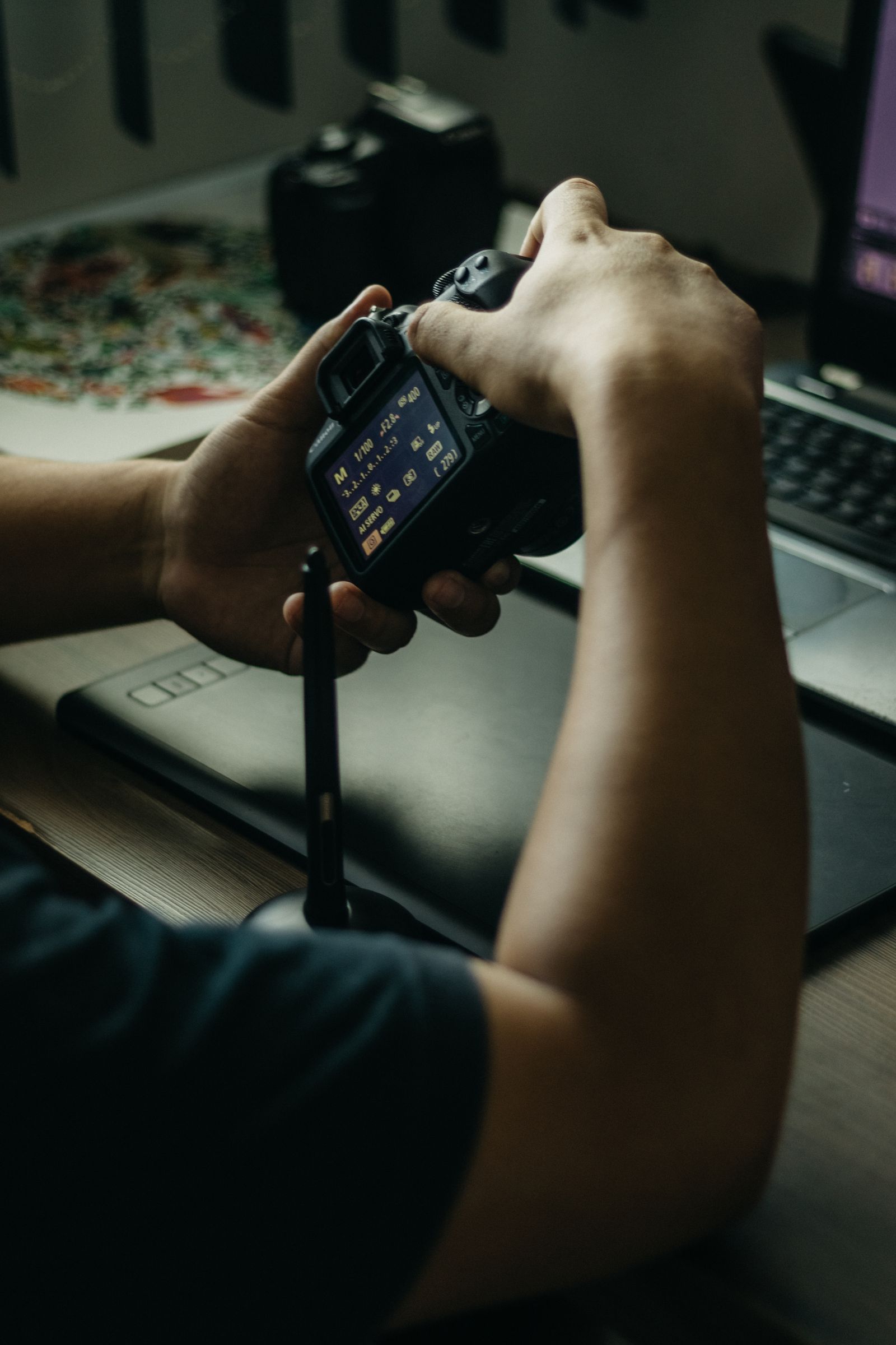 Photographer adjusting a camera beside a laptop
