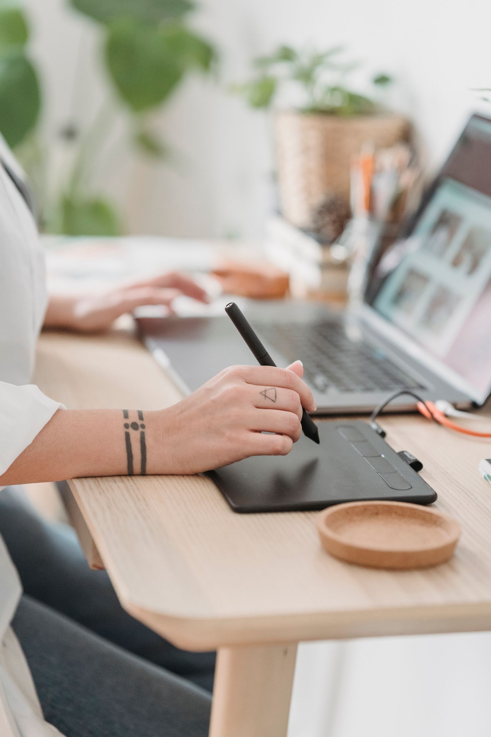 Designer working with a drawing tablet beside a laptop