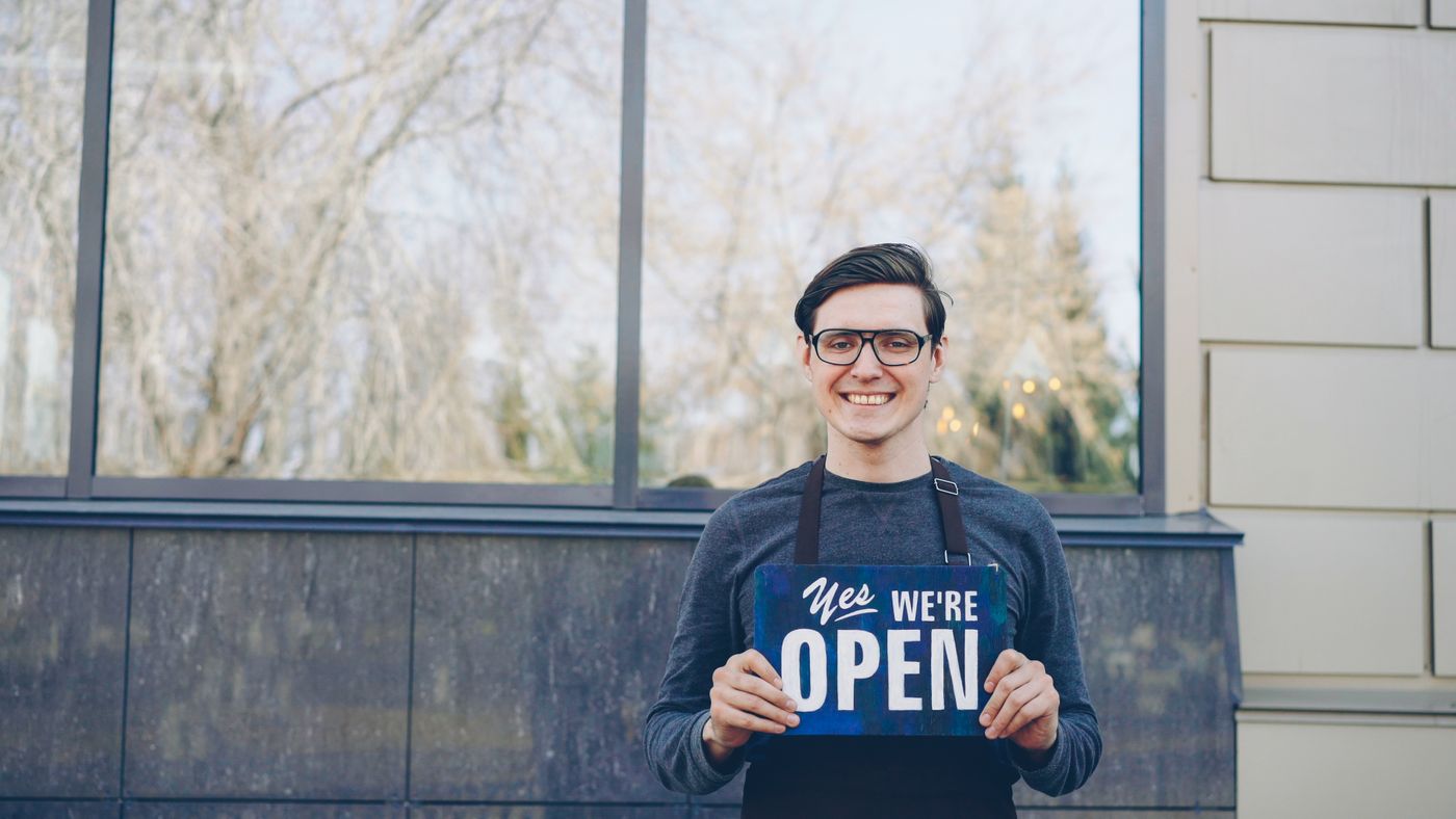 Smiling Business Owner Holding Open Sign Outdoors