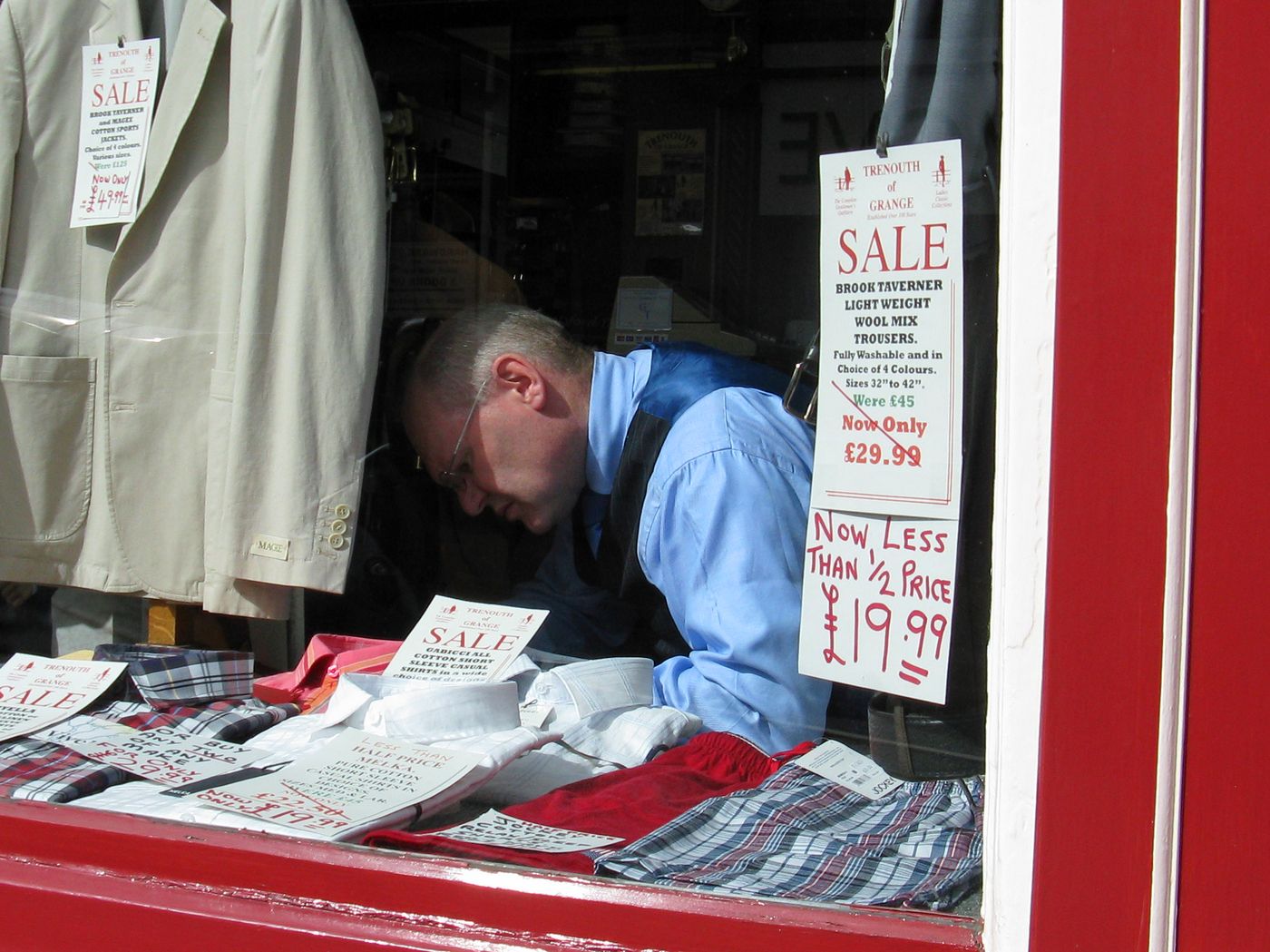 Shopkeeper Arranging Storefront Display in Sale