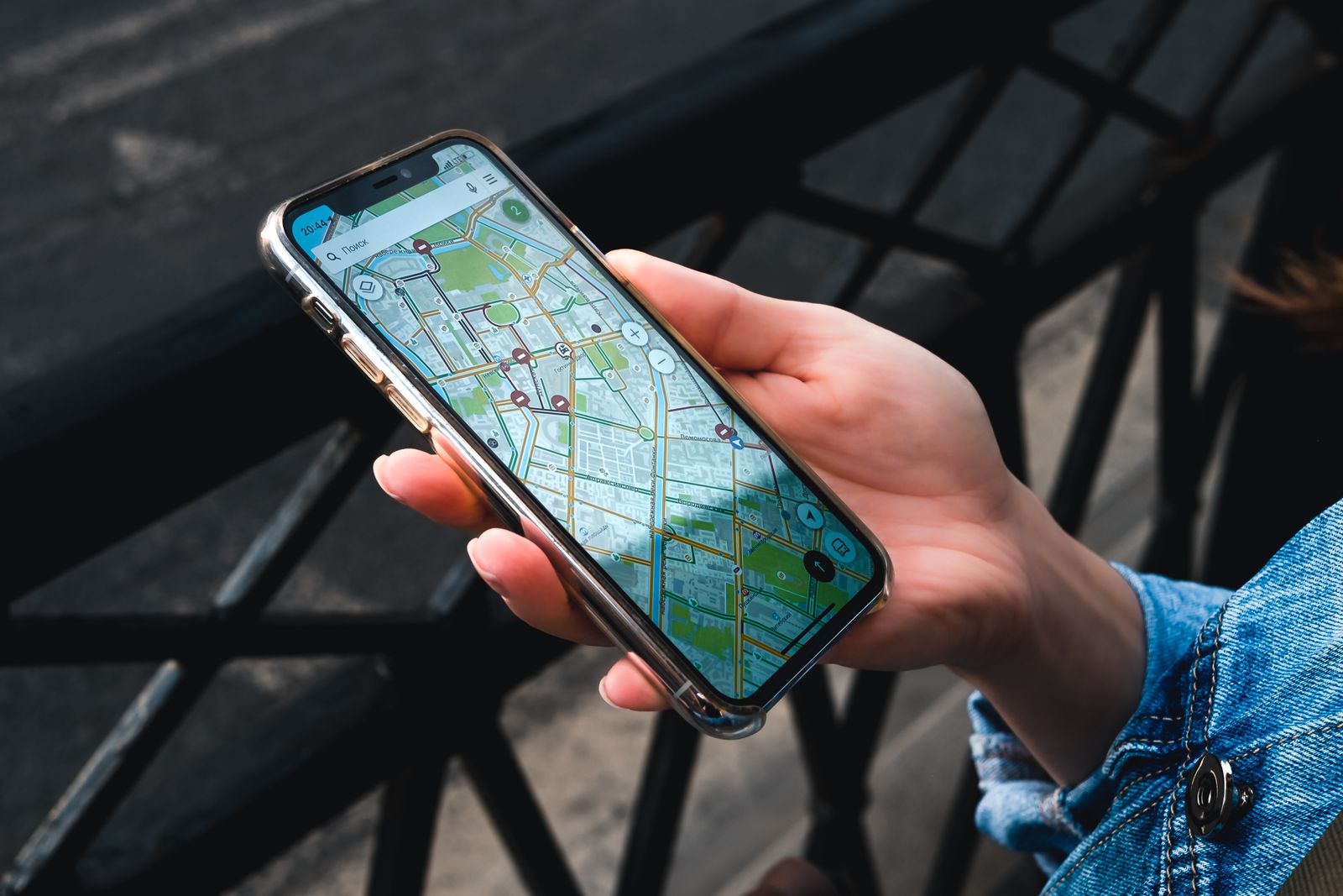Person holding a smartphone displaying a map outdoors