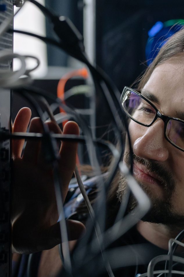 Technician inspecting network connections and computer cables