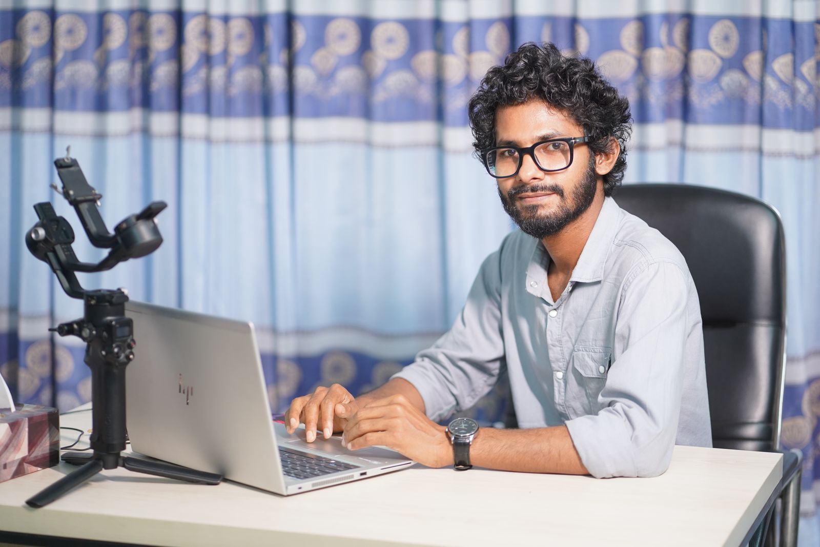 Web professional seated at a desk with a laptop and camera equipment
